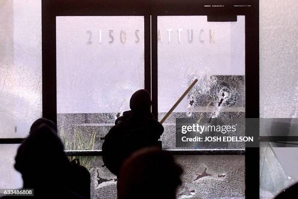 Protester smashes a bank window in Berkeley, California on February 1, 2017. - Violent protests erupted on February 1 at the University of California...