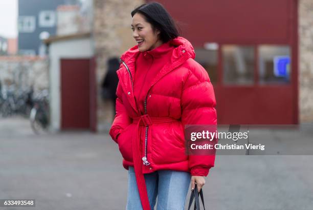 Tiffany Hsu wearing a red down feather jacket, Balenciaga bag, denim jeans outside Baum & Pferdgarten at the Copenhagen Fashion Week Autumn/Winter 17...