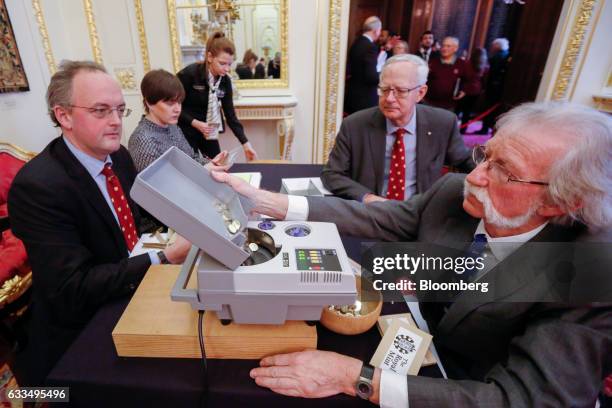 Liverymen of the Goldsmiths' Company, assisted by employees of The Royal Mint Ltd., use a machine to weigh and count coins at the opening of the...