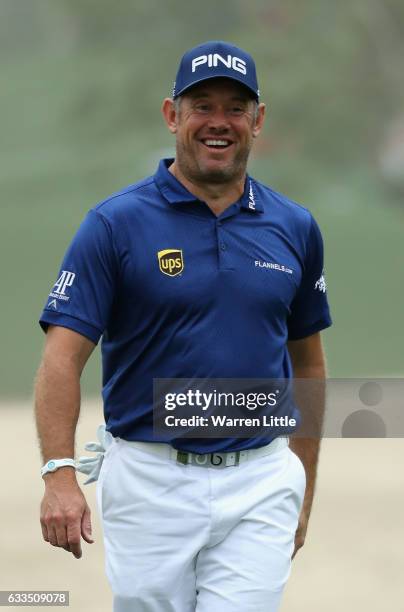 Lee Westwood of England smiles as he runs his ball through the bunker on the 10th hole onto the green during the first round of the Omega Dubai...