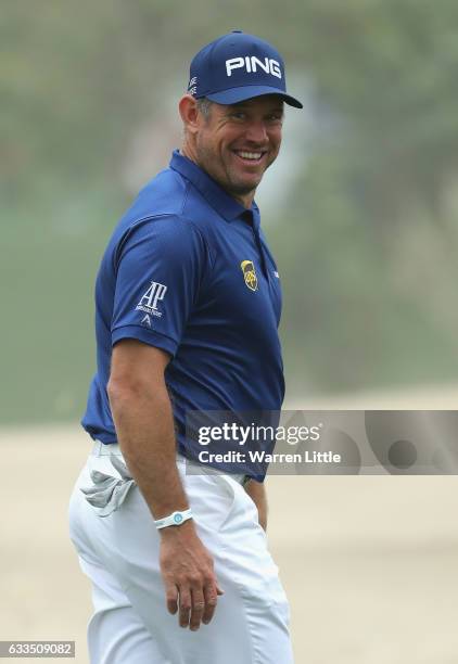 Lee Westwood of England smiles as he runs his ball through the bunker on the 10th hole onto the green during the first round of the Omega Dubai...