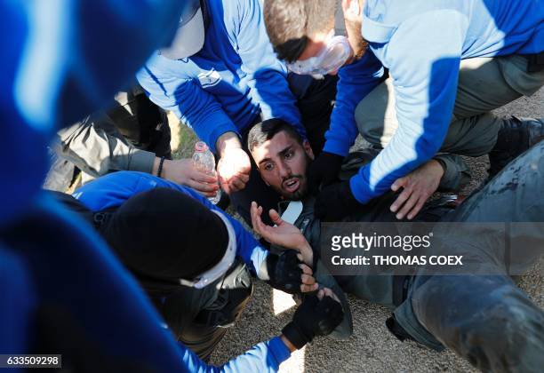 An injured member of the Israeli security forces receives help after being injured on the second day of an Israeli forces operation to evict Jewish...
