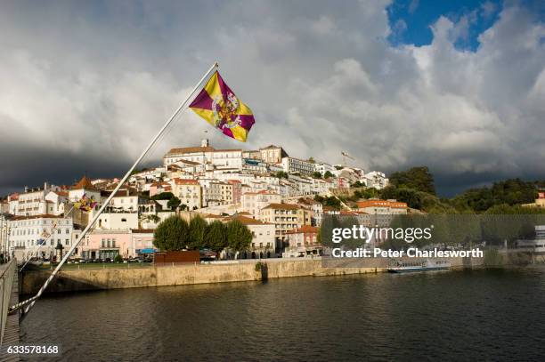 Flag flies in front of a view of the old city from the Ponte de Santa Clara, that crosses the Mondego River in this famous old university town. The...