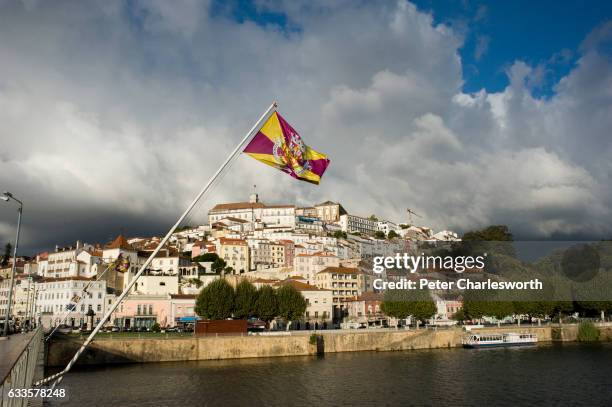 Flag flies in front of a view of the old city from the Ponte de Santa Clara, that crosses the Mondego River in this famous old university town. The...