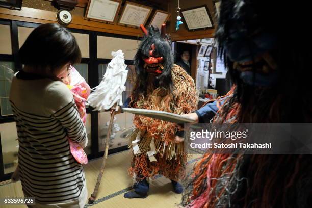 Namahage deities visiting a house during the Namahage festival of traditional folk event on New Year's Eve. They shouting loudly to mother and child...
