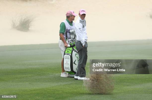 Callum Shinkwin of England laugh as a tumbleweed crosses the eighth fairway during the second round of the Omega Dubai Desert Classic on the Majils...