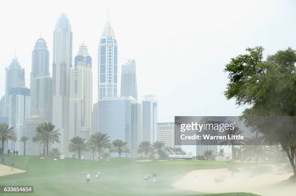 Callum Shinkwin of England turns his back as strong winds blow sand across the eighth fairway during the second round of the Omega Dubai Desert...