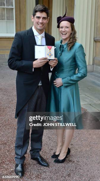 England cricket captain Alastair Cook poses with his wife Alice as he holds his medal after being appointed a Commander of the Order of the British...