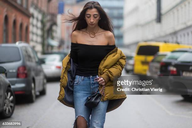 Nadja Ali wearing a black off shoulder Brandy Mellville shirt, a Sabrina Dehoff necklace, ripped Levis denim jeans, net tights Wolford, a mustard...