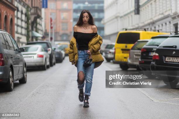 Nadja Ali wearing a black off shoulder Brandy Mellville shirt, a Sabrina Dehoff necklace, ripped Levis denim jeans, net tights Wolford, a mustard...