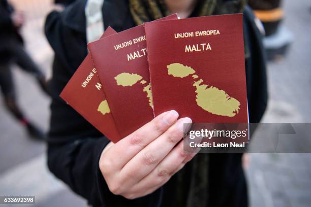 Woman holds a mock passport of Malta, containing a call for an end to the threat of deportation of a group of Malian migrants, outside the venue of...