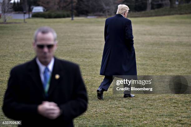 Member of the Secret Service stands watch as U.S. President Donald Trump walks toward Marine One on the South Lawn of the White House in Washington,...