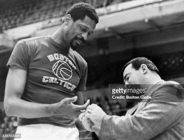 Boston Celtics trainer Joe DeLauri looks at player Bill Russell's fingers on April 6, 1968.