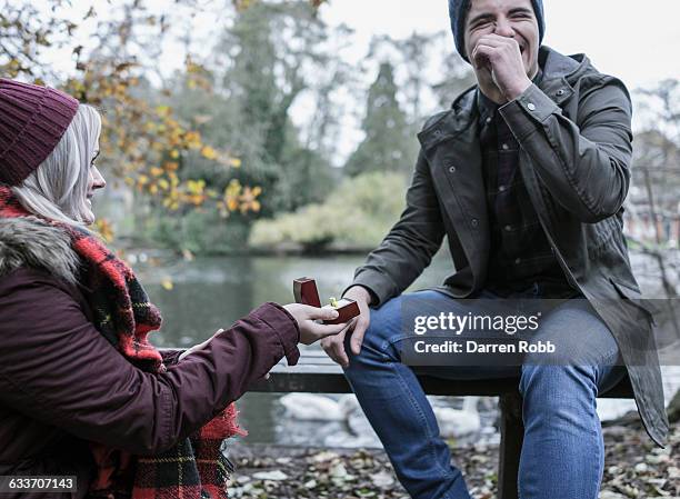 woman proposing to a man on a park bench - 訂婚戒指 個照片及圖片檔