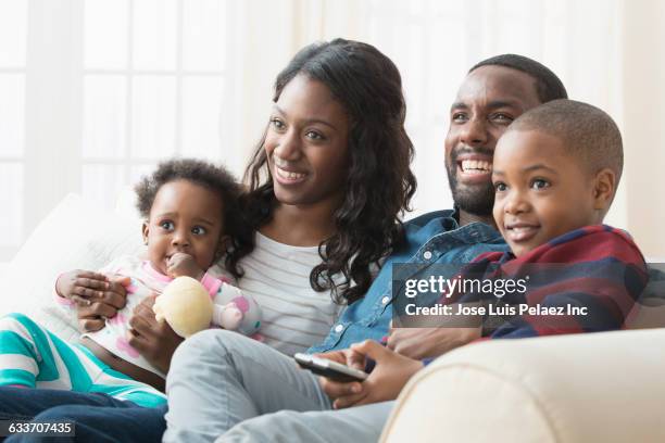 family watching television on sofa - african watching tv stock pictures, royalty-free photos & images