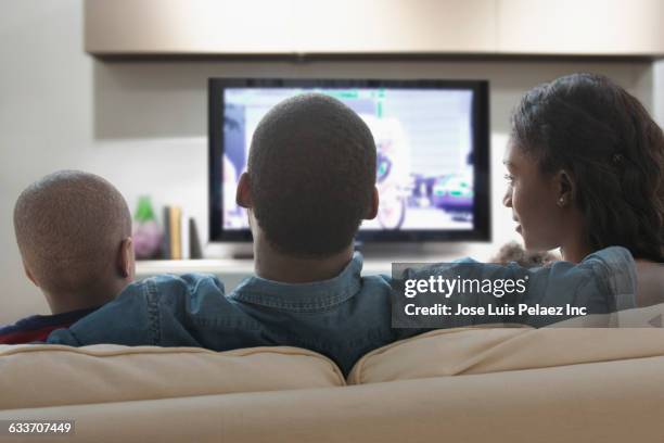 family watching television on sofa - couple watching tv photos et images de collection