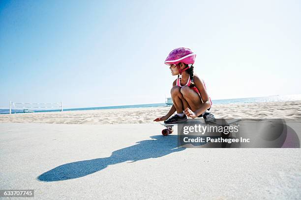 mixed race girl riding skateboard at beach - skateboard foto e immagini stock