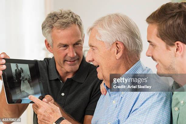 three generations of caucasian men using digital tablet - alzheimer's disease stock pictures, royalty-free photos & images