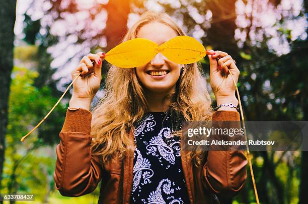 caucasian woman playing with autumn leaves - mysterious blond woman stock pictures, royalty-free photos & images