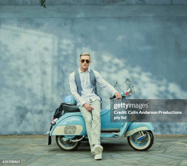 caucasian man sitting on vintage scooter - roller vintage stock-fotos und bilder