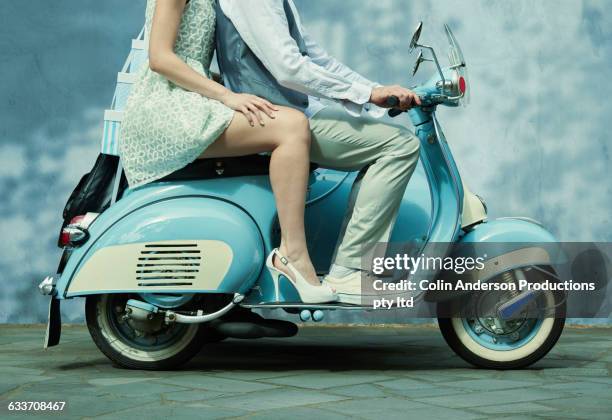 couple riding vintage scooter - breitbeinig stock-fotos und bilder