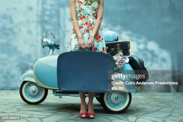 pacific islander woman holding suitcase near vintage scooter - blue dress fotografías e imágenes de stock