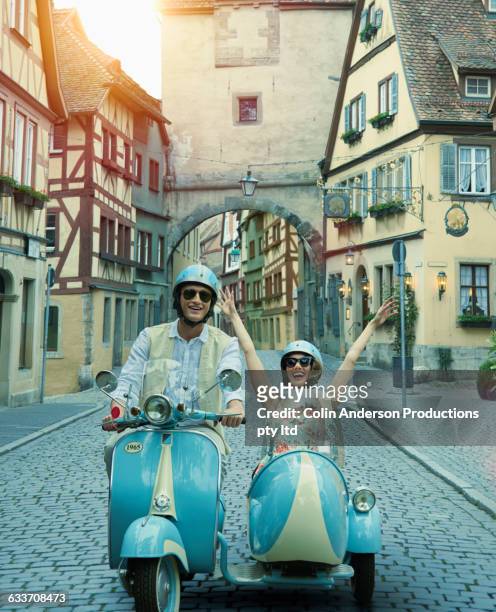 couple driving vintage scooter and sidecar in village - roller vintage stock-fotos und bilder