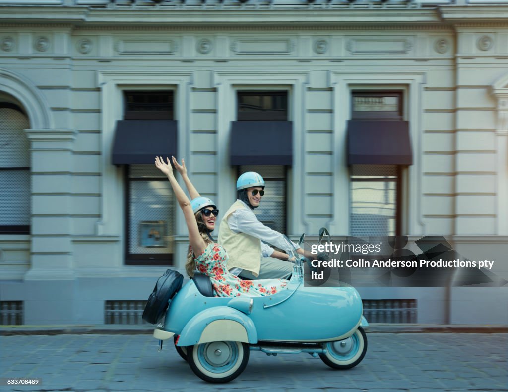 Couple driving vintage scooter and sidecar
