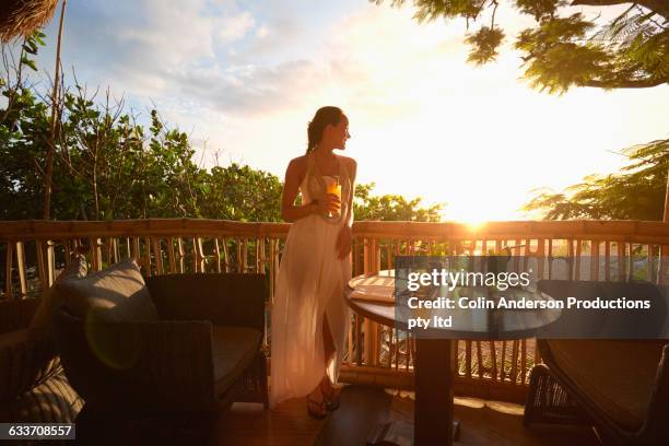 pacific islander woman admiring sunrise from patio - restaurant patio stockfoto's en -beelden