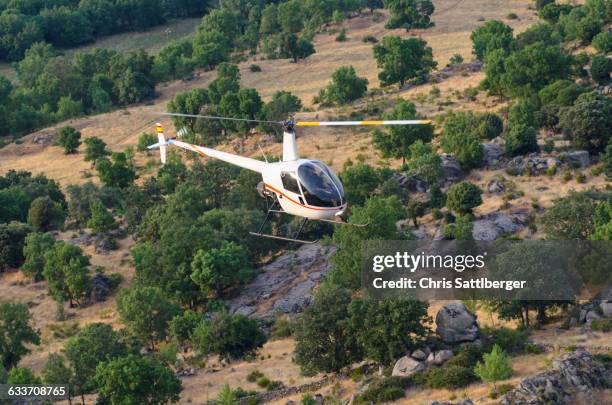 aerial view of helicopter flying over remote landscape - helicóptero fotografías e imágenes de stock