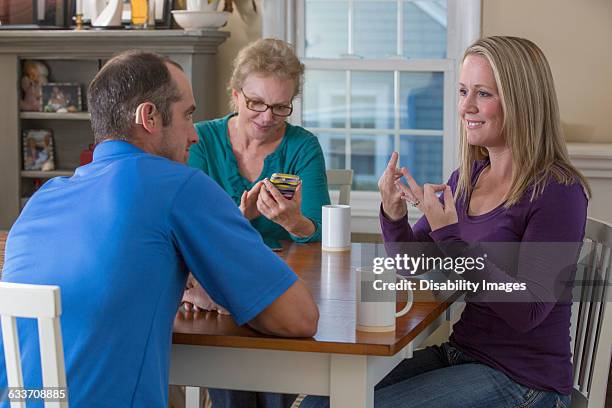 deaf caucasian friends signing at dinner table - deafness stock pictures, royalty-free photos & images