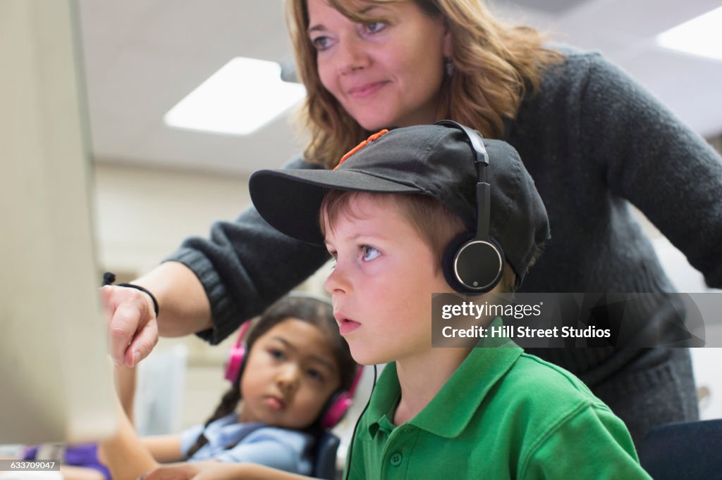 Teacher helping students use computers in classroom