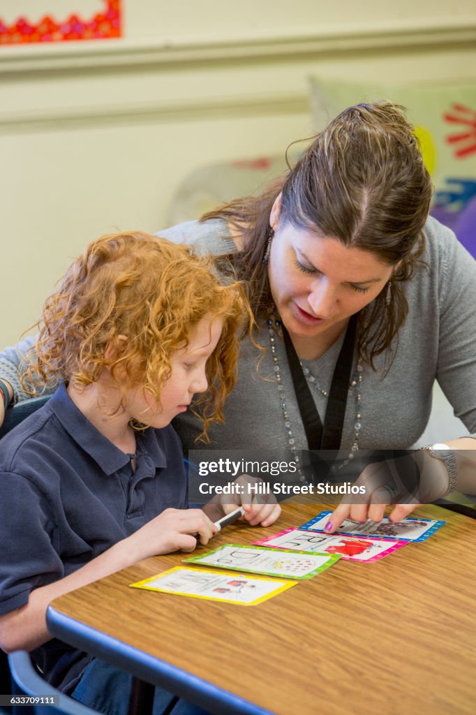 Teacher helping student with project in classroom