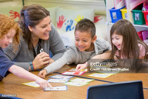 teacher helping students with project in classroom - flash card stock pictures, royalty-free photos & images