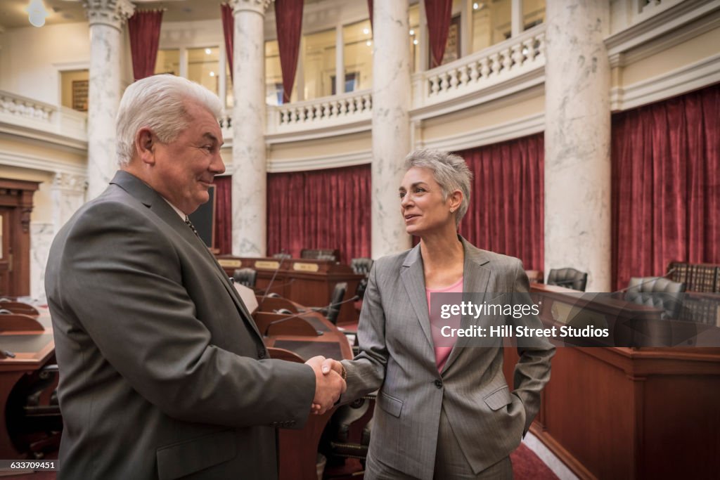Caucasian politicians shaking hands in capitol building