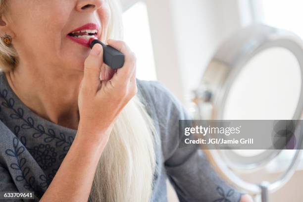 caucasian woman applying makeup in mirror - applying lipstick ストックフォトと画像