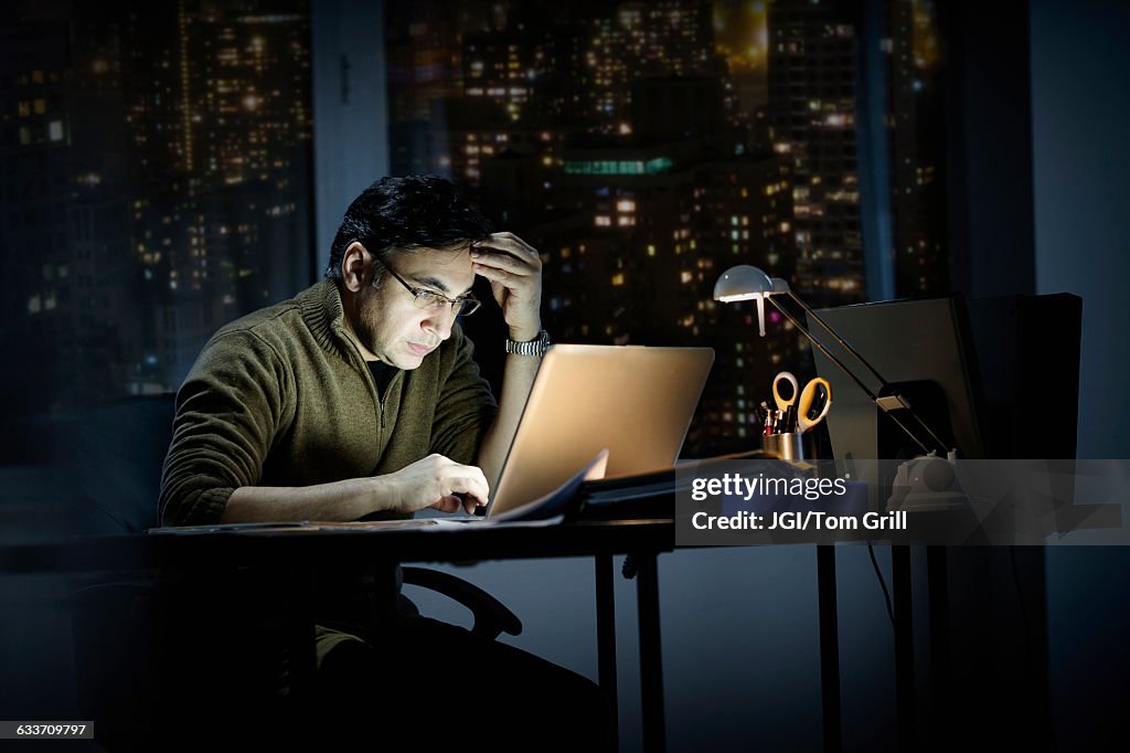 Mixed race businessman working late in office