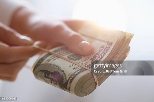 hispanic woman holding rubber band around wad of cash - counting money woman stock pictures, royalty-free photos & images