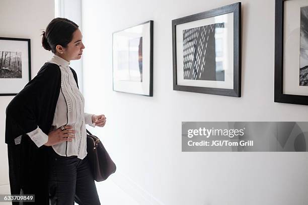 hispanic woman admiring art in gallery - exhibition stock-fotos und bilder