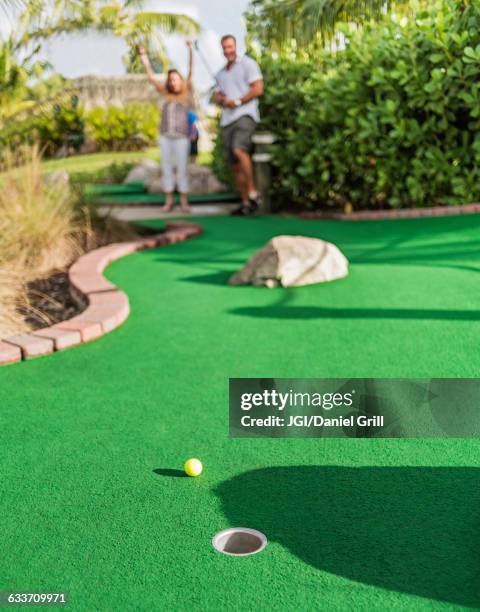 caucasian couple playing miniature golf - minigolf stockfoto's en -beelden