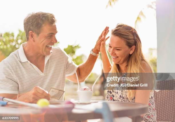 caucasian couple high-fiving at outdoor table - debt free stock pictures, royalty-free photos & images