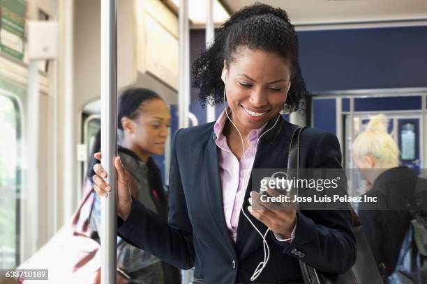 businesswoman listening to earphones on train - femme metro photos et images de collection