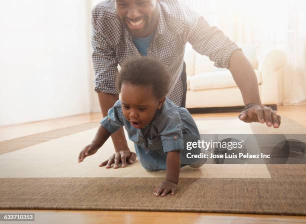 father and baby daughter crawling on rug - baby on the move stock pictures, royalty-free photos & images