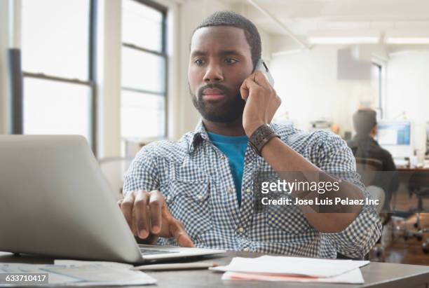 african american businessman multitasking in office - answering email stock pictures, royalty-free photos & images