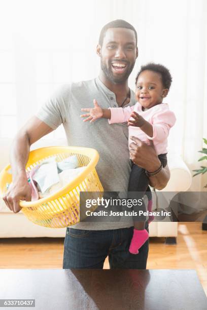 father holding baby daughter and laundry basket - man washing basket child stock pictures, royalty-free photos & images