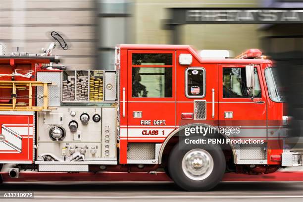 blurred view of fire truck driving in city - brandweerwagen stockfoto's en -beelden