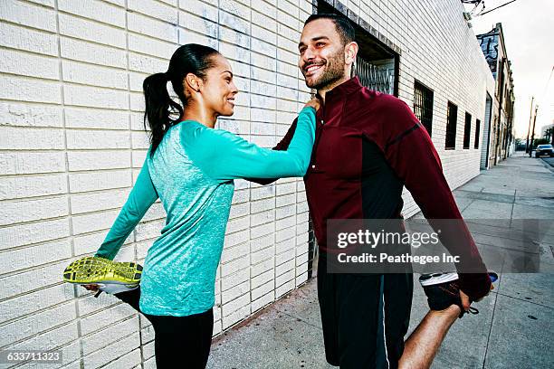 athletic couple stretching on sidewalk - active lifestyle los angeles stock pictures, royalty-free photos & images