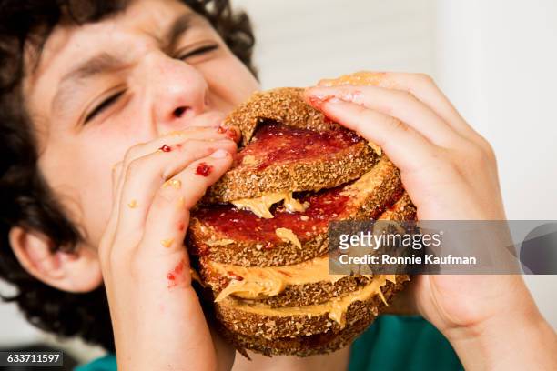 caucasian boy eating oversized sandwich - beurre de cacahuètes photos et images de collection