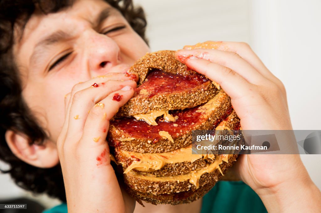 Caucasian boy eating oversized sandwich