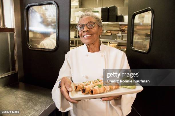 black chef holding plate of food in restaurant - catering black uniform stockfoto's en -beelden